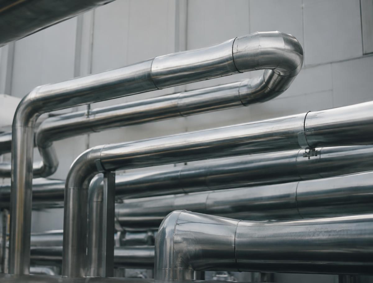 Stainless steel industrial pipework in soft light